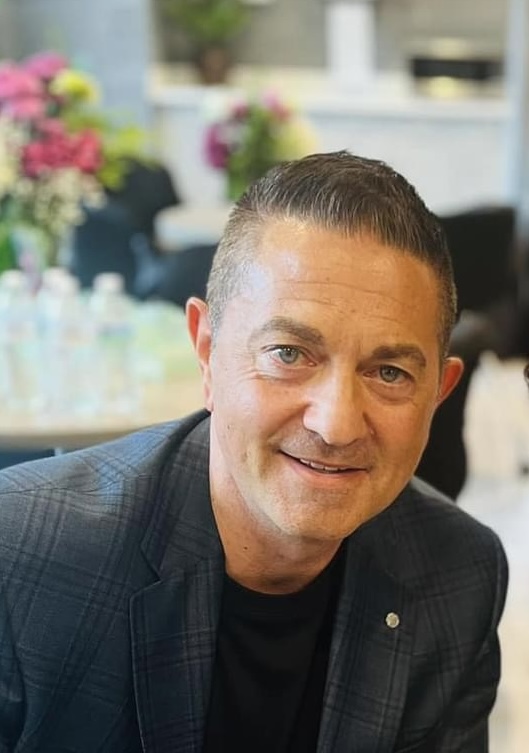 A photo of Harry Psaros at an event hall wearing a suit