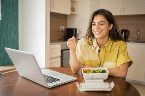 a woman smiling at her laptop screen sipping coffee